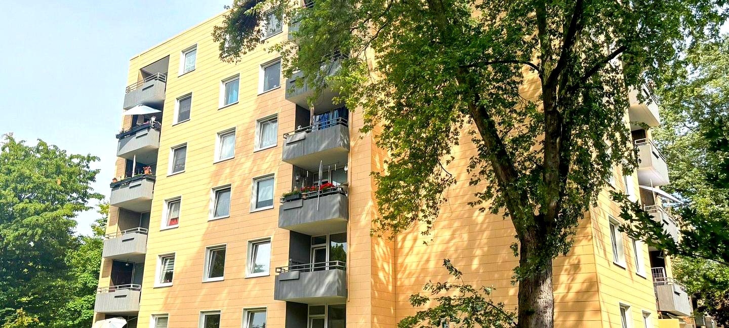 Mehrfamilienhaus in Düsseldorf mit Balkonen und großem Baum vor der Fassade