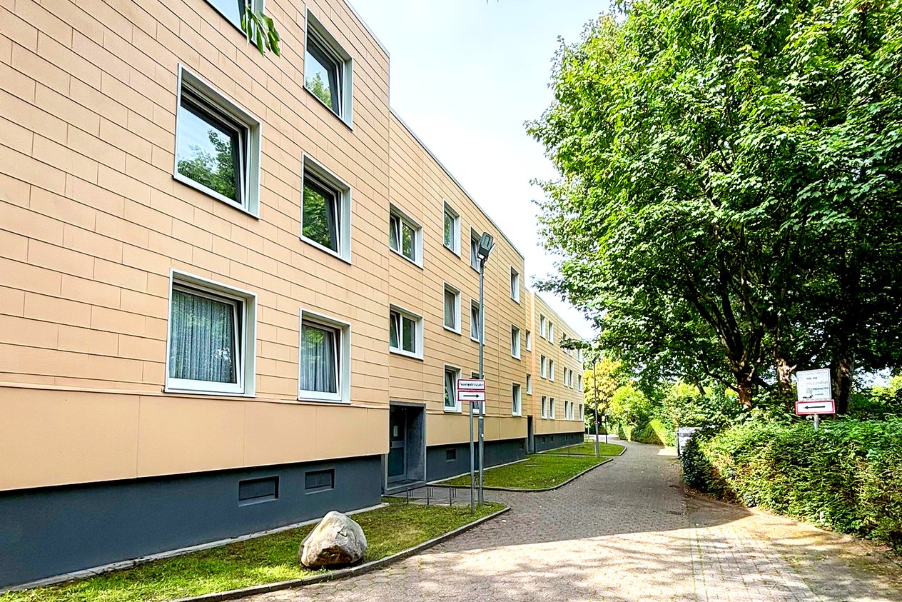 Gepflasterter Zugang zum Mehrfamilienhaus in Düsseldorf mit Grünflächen