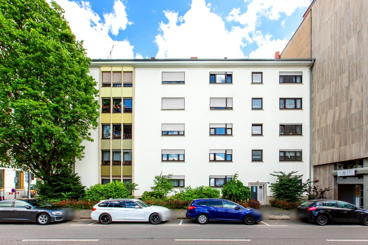 Weißes Mehrfamilienhaus in Ludwigshafen mit Hecke und Parkplätzen