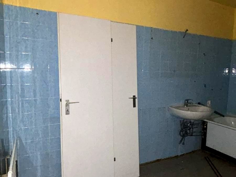 Badezimmer vor der Sanierung mit blauen Fliesen und altem Waschbecken