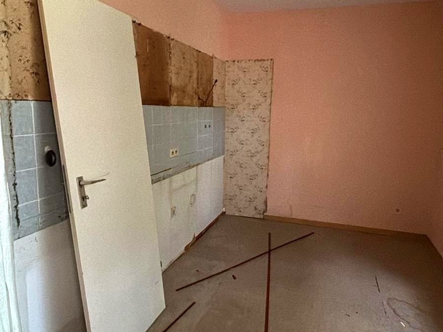 Küche vor der Sanierung, entkernt, mit altem Fliesenspiegel