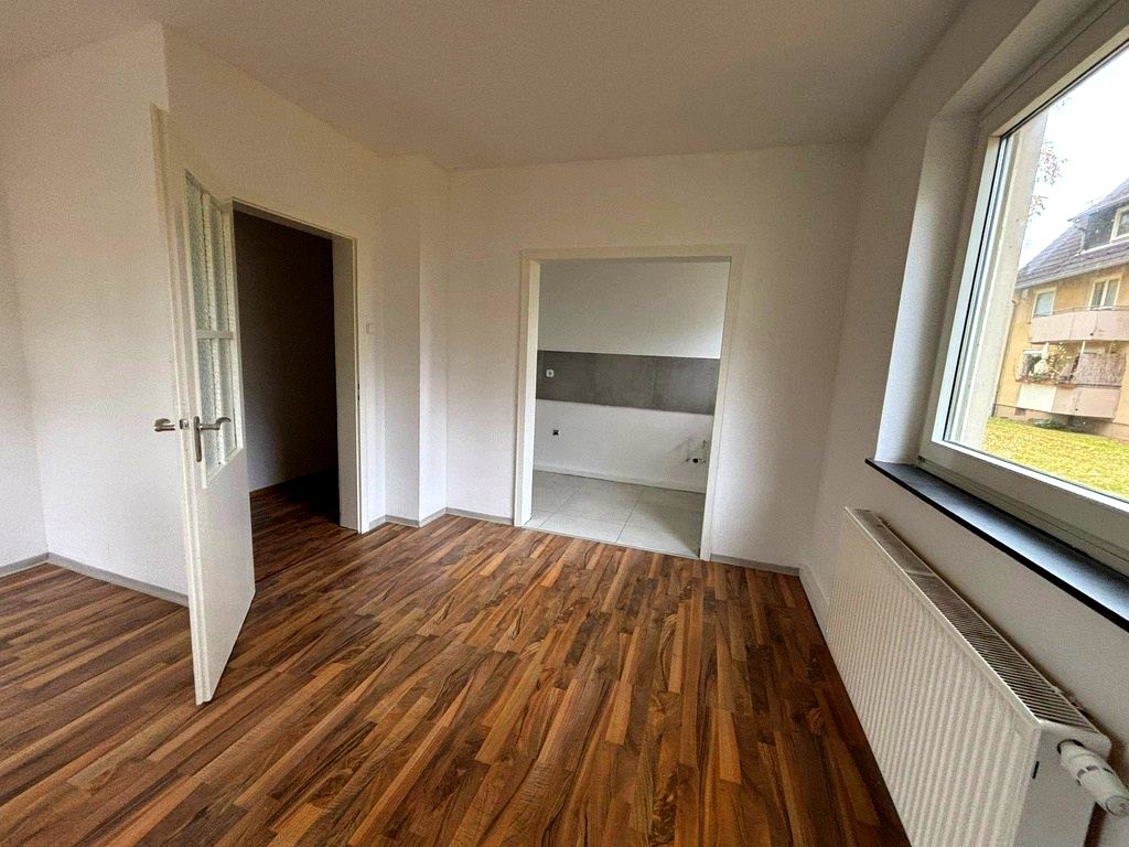 Derselbe Wohnraum nach der Sanierung mit weißen Wänden und neuem Holzboden